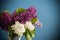 bouquet of different blooming spring lilacs in a vase on blue background