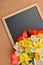 Bouquet of different daffodils and red and yellow tulips on blank blackboard, over cork background. Selective focus. Space for te