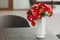 A bouquet of different red flowers in a vase on a table. Close-up. Artwork