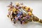 Bouquet of dried, colored flowers lying on a white background of the table.