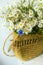 a bouquet of field daisies and cornflowers in a vintage wicker bag