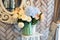 Bouquet of flowers in a blue vase on a table against the background of a mirror and a wooden wall in an interior