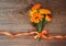 Bouquet from flowers of calendula with ribbon on wooden background