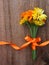 Bouquet from flowers of calendula with ribbon on wooden background