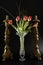 Bouquet of flowers and candlesticks on black background, faded tulips studio photo, five tulips in a vase and two bronze candlesti