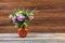 Bouquet of flowers of clover, cornflowers and Jasmine in a earthenware jug on a wooden table on a brown retro background