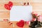 Bouquet of flowers, handmade red thread hearts and white mockup blank on wooden table, cope space.