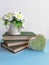 Bouquet of flowers on old books, decorative heart on blue desk on white background