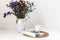 Bouquet of flowers, open book and glasses, lemon tea in a white ceramic cup on a wicker stand on the table, cozy home interior