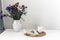 Bouquet of flowers, open book and glasses, lemon tea in a white ceramic cup on a wicker stand on the table, cozy home interior