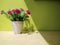 A bouquet of flowers in a vase on a wooden table and a green backdrop by the window and sunlight.