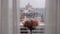 A bouquet of flowers is on the windowsill and a big city is visible outside the window.