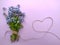 A bouquet of forget me nots tied with a rope of jute on a lilac background