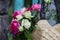 Bouquet of fragrant English pink and white roses in a bag of raffia hanging on the fence