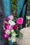 Bouquet of fragrant English pink and white roses in a bag of raffia hanging on the fence