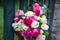 Bouquet of fragrant English pink and white roses in a bag of raffia hanging on the fence