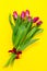 Bouquet of fresh beautiful lila tulips on yellow colorful background. Spring concept. Horizontal, top view with copy space.