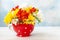 Bouquet of fresh multicolored freesias in a red vase