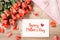 Bouquet of fresh pink red roses with gift on wooden background. Floral romantic arrangement with card text Happy Mother\'s Day