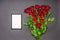 Bouquet of fresh red rose flowers and empty photoframe on black background. Floral composition, mourning card for event, mock up.