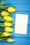 Bouquet of fresh tulips on blue wooden background, copy space for text on sheet of paper