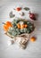 Bouquet of fresh vegetables lies on a white wooden table. Nearby is a red onion, tomatoes, garlic, bay leaf. View from above. Tone