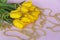 A bouquet of fresh yellow tulips. A bouquet of tulips on a pink background with a scattering of gold beads. Spring flowers in the