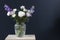 Bouquet of hackelia velutina, purple and white roses, small tea roses, matthiola incana and blue iris in glass vase