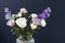 Bouquet of hackelia velutina, purple and white roses, small tea roses, matthiola incana and blue iris in glass vase . Dark blue