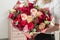 Bouquet of highly red coloured . beautiful luxury bunch of mixed flowers in womans hand. the work of the florist at a