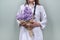 Bouquet of lilac flowers in the hands of female doctor with stethoscope