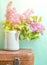 Bouquet of lilac in an old enameled teapot on vintage suitcase on blue background. Retro style still life.