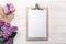 A bouquet of lilacs with tablet, gift box and craft envelope on white boards