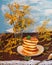 A bouquet of mimosa in a glass vase and a pile of pancakes with a brown napkin on a table