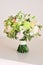 Bouquet of mint and peach colors on wooden table. White freesia, green dianthus, peach roses, light chrysanthemum and fresh greens