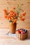 Bouquet of orange lilies in clay vase and fruits in wicker basket