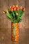 Bouquet of orange tulips in glass colorful vase