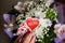 Bouquet of orchids, Lisianthus,Gypsophila.Female hand is holding a big red heart with text mom, Present with love