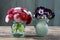 Bouquet of pansy flowers in ceramic vase and bouquet of red daisies in glass vase