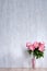 Bouquet of peonies in a vase against a blue wall.