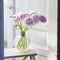 Bouquet of Pink Persian buttercups is in glass round vase on a white wooden tall chair