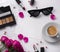 Bouquet of pink roses, cup of coffee, sunglasses, concealer and lipstick on white table.