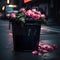 Bouquet of pink roses thrown into street garbage can. Black and dirty garbage can with roses thrown there.