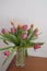 bouquet of pink and yellow tulips in vase closeup across white all on the wooden drawer. Interior detail. Hotel interior