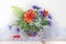 Bouquet with poppies, cornflowers, snowdrops in a vase on a white background