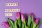 Bouquet of purple tulips and wood letters on violet background.