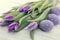 Bouquet of purpleviolet tulips and painted easter eggs on white rustic wooden background with copy space for message. Holiday
