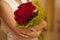Bouquet of red or crimson roses in hands of woman