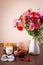 Bouquet of red and pink poppy and blue cornflower in a jug with tasty breakfast.