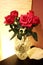 A bouquet of red roses in a crystal vase in the evening on a table in brown and beige tones